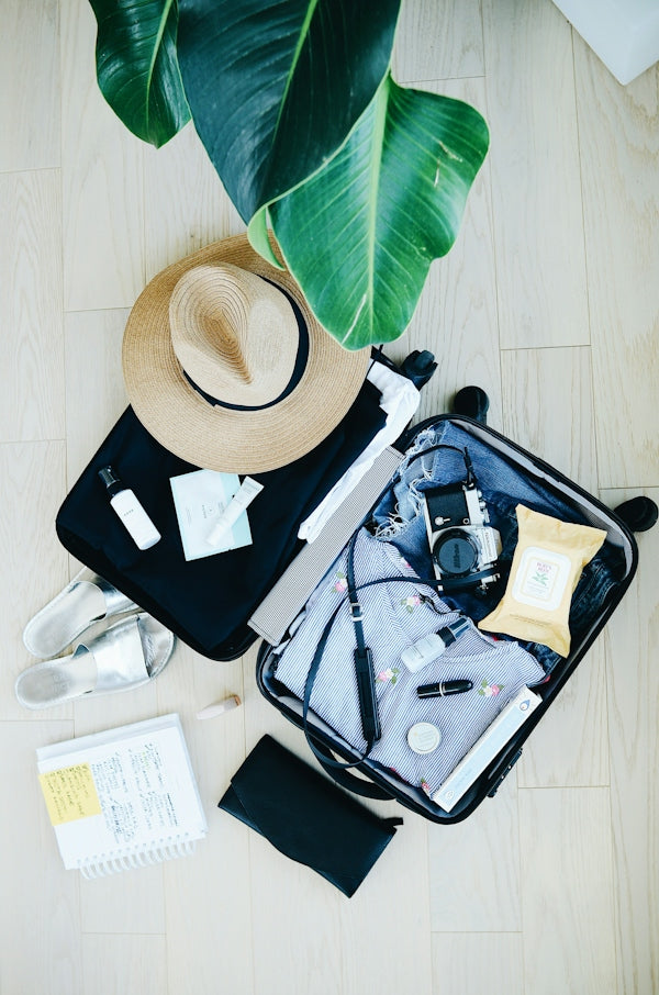 open suitcase with travel essentials and hat