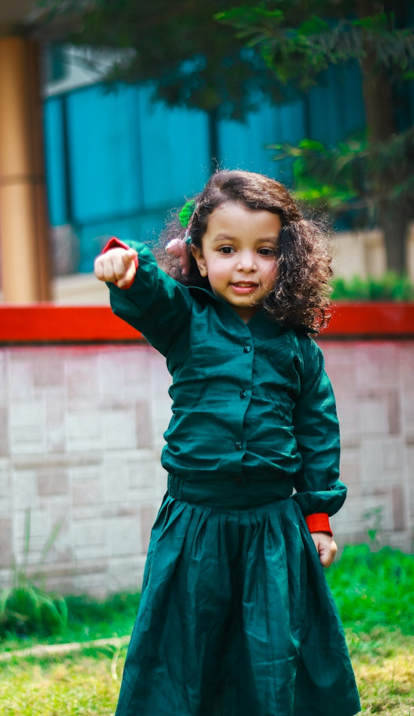 A smiling child points forward with a playful gesture