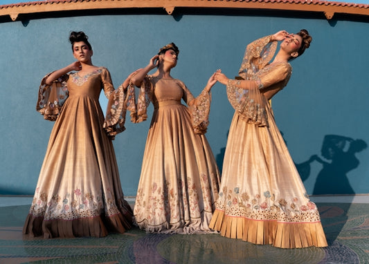 Three women in elegant gold gowns posing together