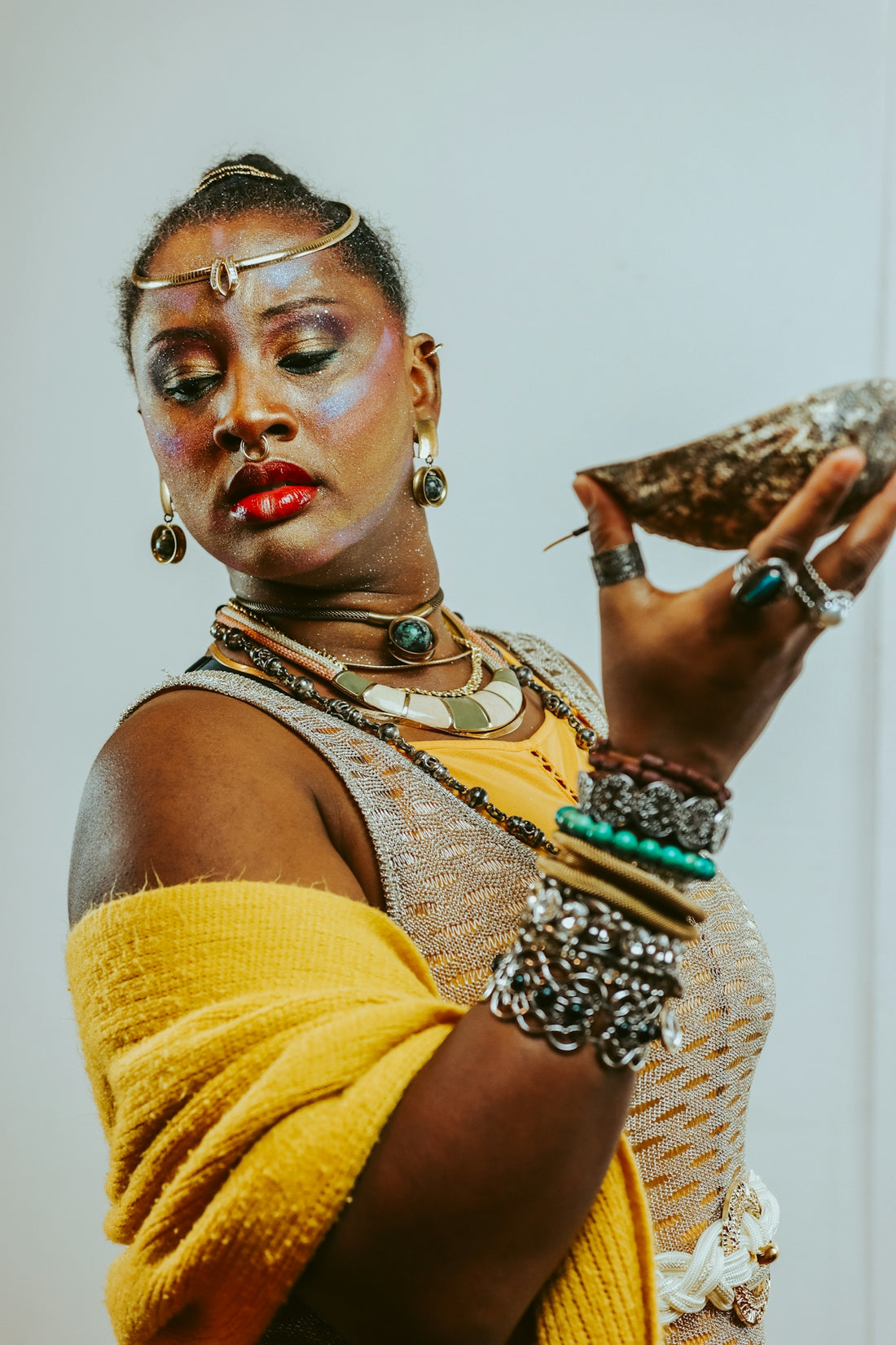 Woman in elaborate jewelry holds a seashell